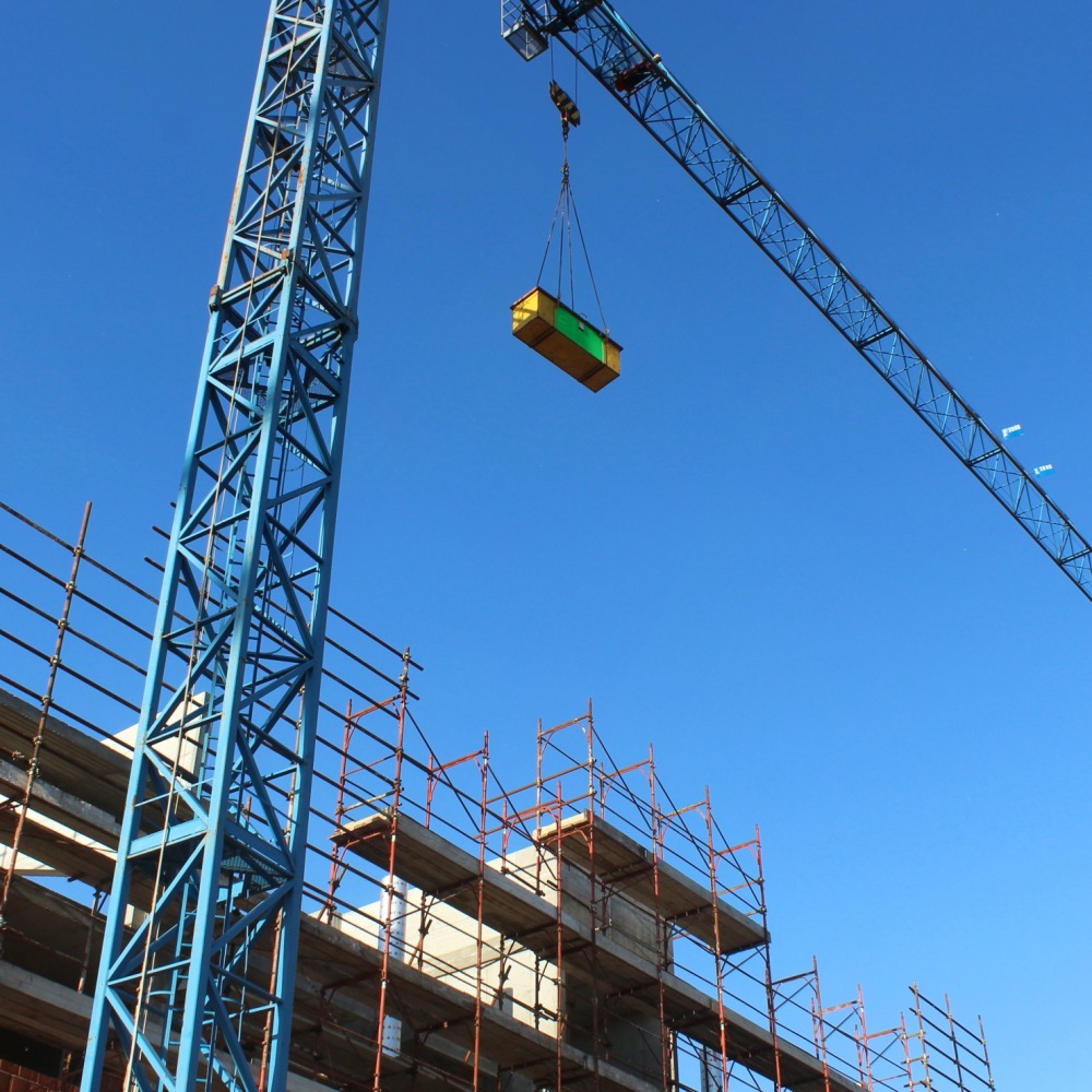 A view of  construction site with tall tower crance with a blue sky on a sunny day